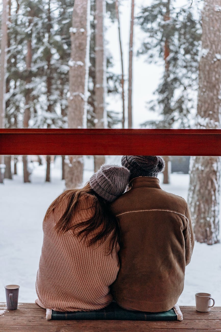 couple sitting on porch with snowy forest background